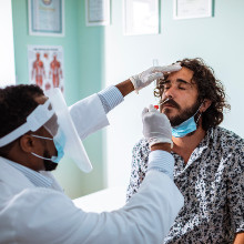 Un homme réalise un test de dépistage Covid-19 auprès d’un professionnel de santé