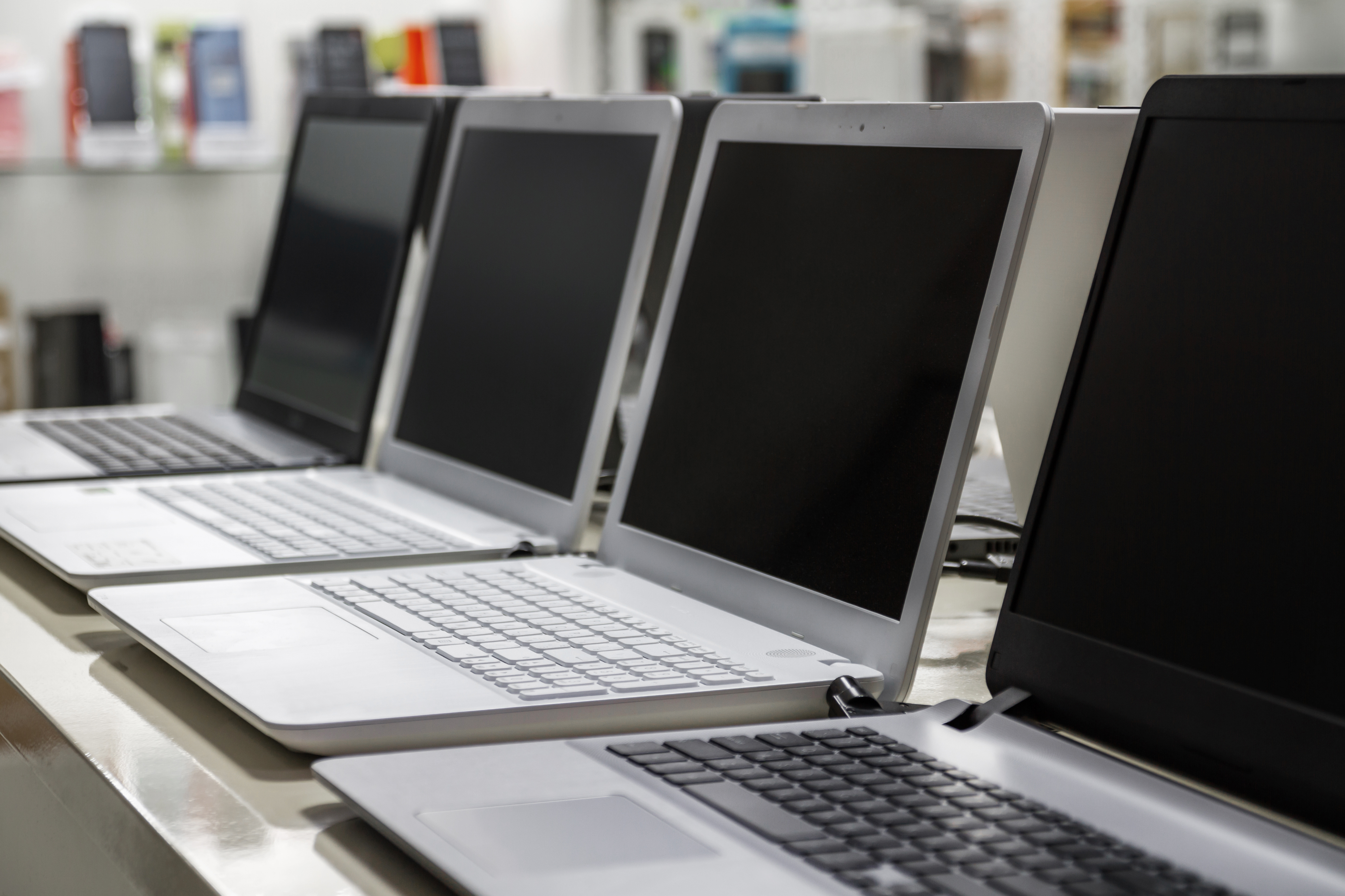 4 ordinateurs portable ouverts sur un bureau posés côte à côte