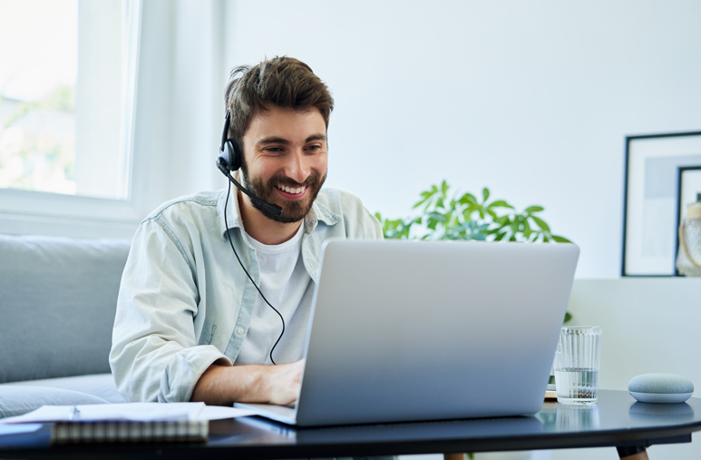 Homme assis sur une chaise devant un bureau avec un ordinateur en situation de télétravail