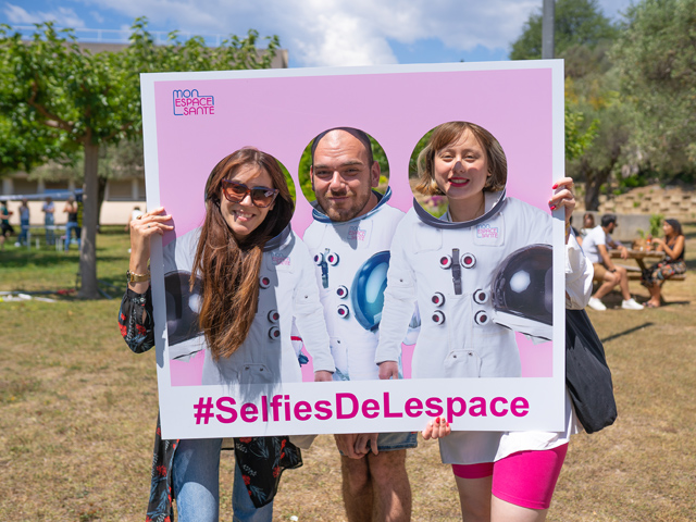 Photo de 3 collaborateurs qui prennent la pose en tenant une pancarte avec les mains 