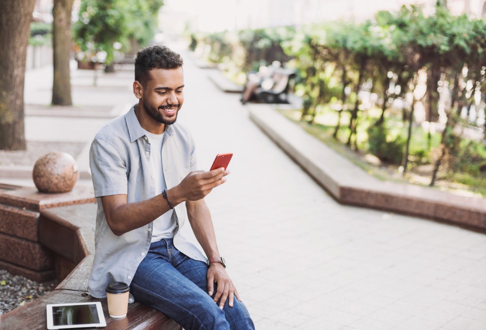 Photo d'un jeune homme utilisant les téléservices sur son smartphone et sa tablette