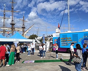 Vue du Village Mes tips santé sur l’esplanade Eric Tabarly à La Rochelle avec des passants et le bus Mes tips santé.