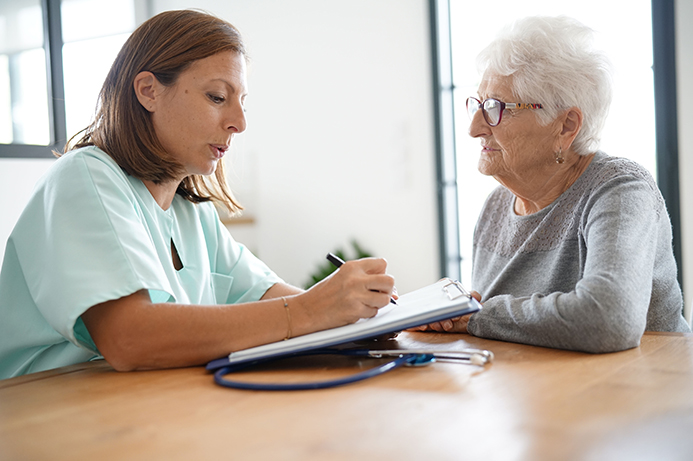 Une infirmière discute avec une personne âgée à son domicile