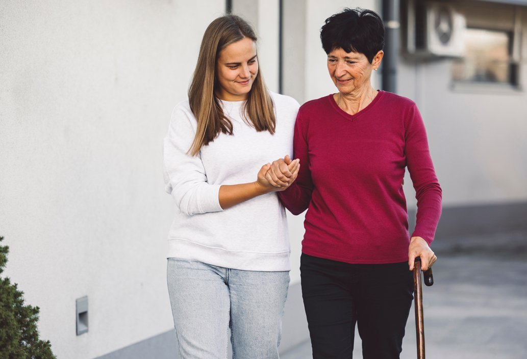 Une dame avec une canne est guidée par une jeune femme