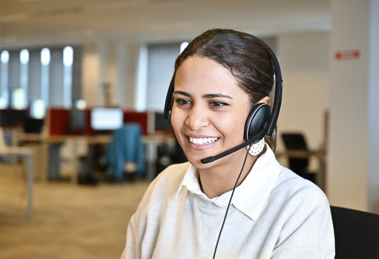 photo : une conseillère de l’Assurance Maladie répond au téléphone, un casque audio sur le tête