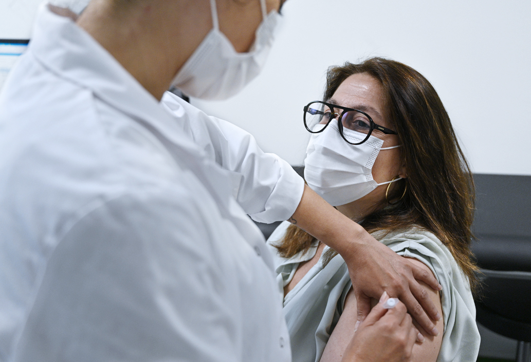 Une infirmière du centre d'examens de santé vaccine une dame masquée