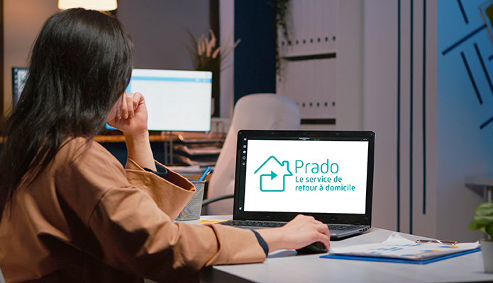 Une femme est devant un ordinateur avec le logo Prado