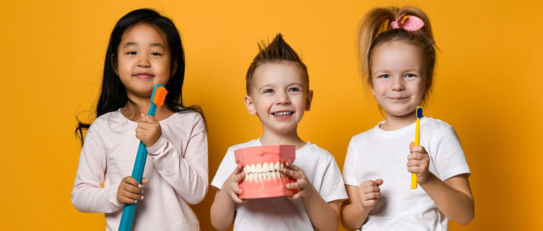 3 enfants avec des brosse a dents géantes représentant le programme M’T Dents 