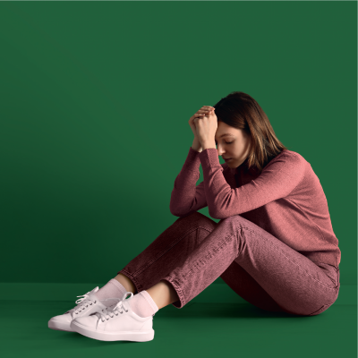 jeune femme assise par terre appuyant son front contre ses mains jointes