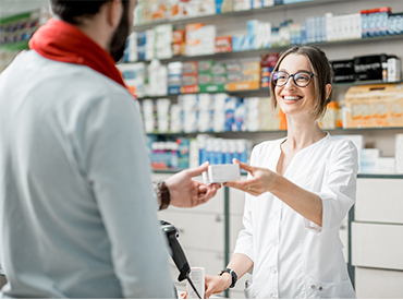 Photo d'une pharmacienne remettant un médicament à un client.