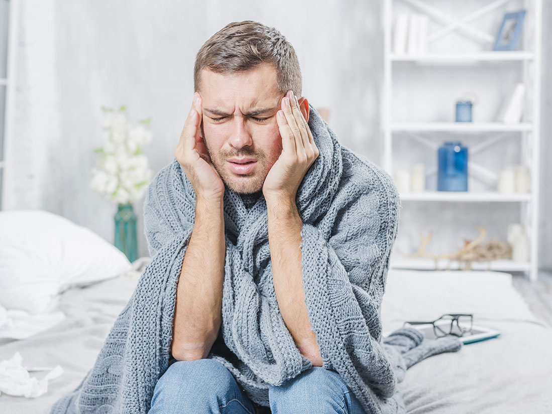 Photographie d'un homme malade qui se tient la tête.